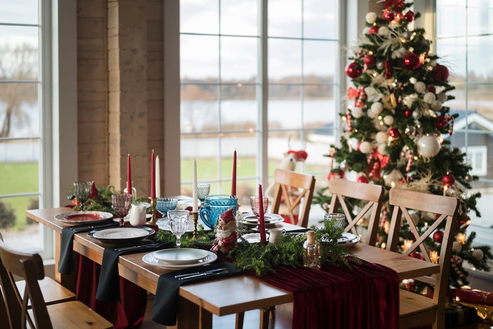 Table de fête décorée d'une guirlande verte au centre et de bougies