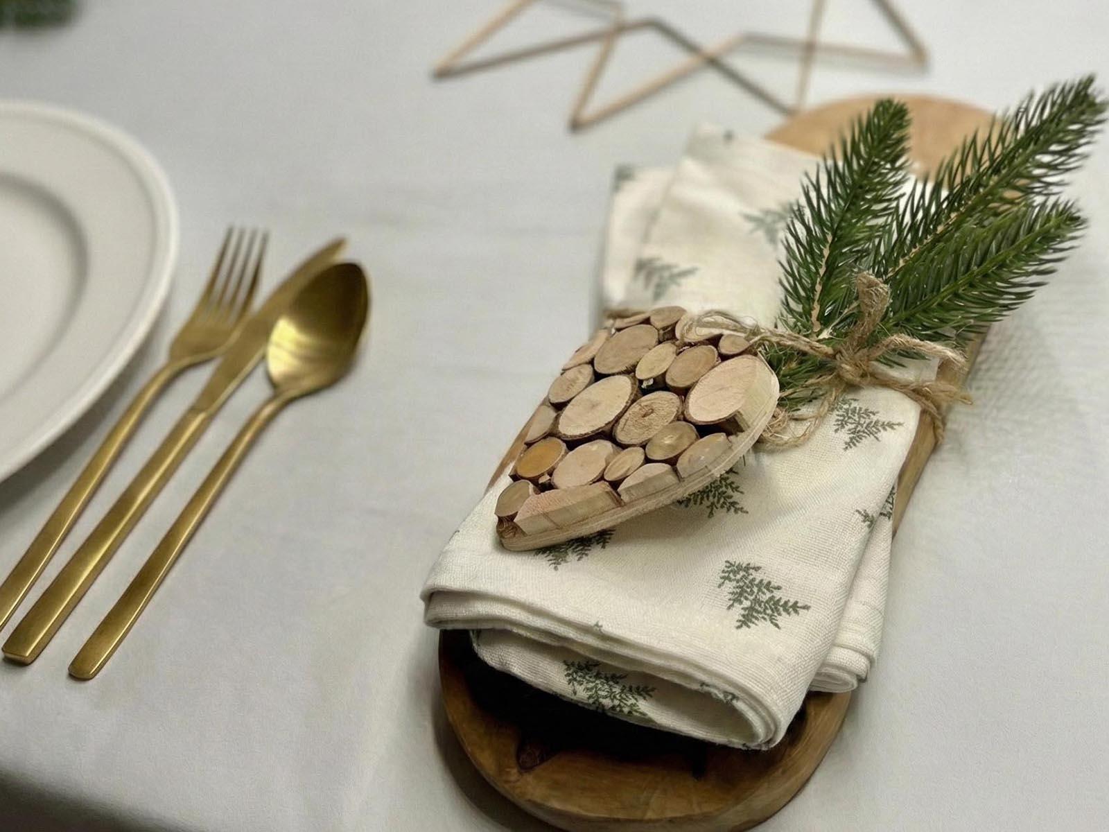 Une branche de sapin artificiel FairyTrees attach&eacute;e &agrave; une serviette enroul&eacute;e avec un c&oelig;ur en bois et une ficelle constitue une excellente fa&ccedil;on de r&eacute;utiliser un ancien sapin.