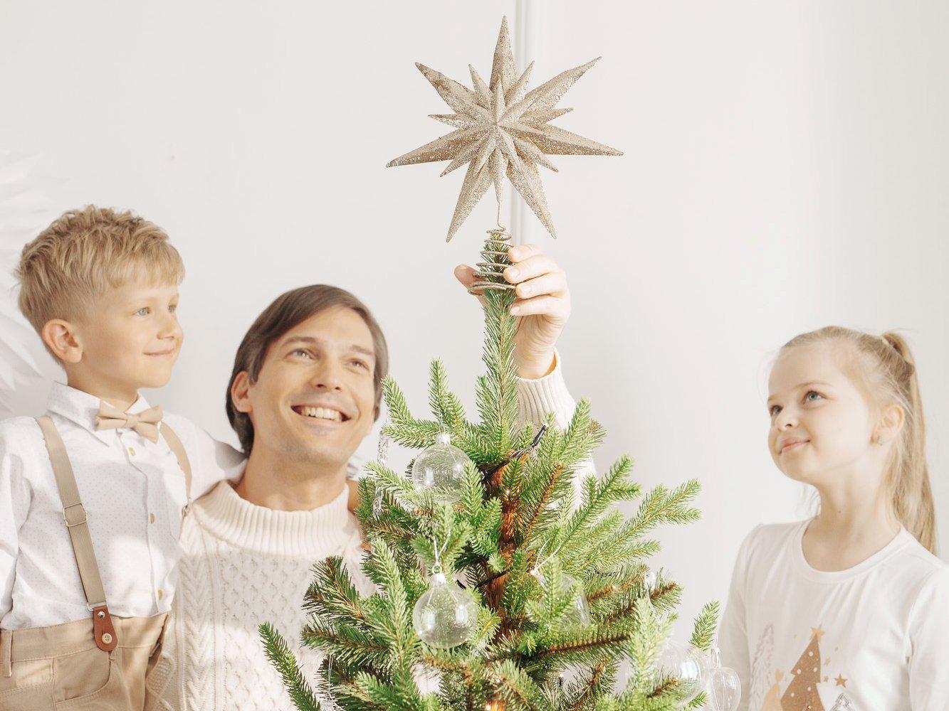 Papa place une étoile au sommet du sapin artificiel FairyTrees FT32 en compagnie de ses enfants.