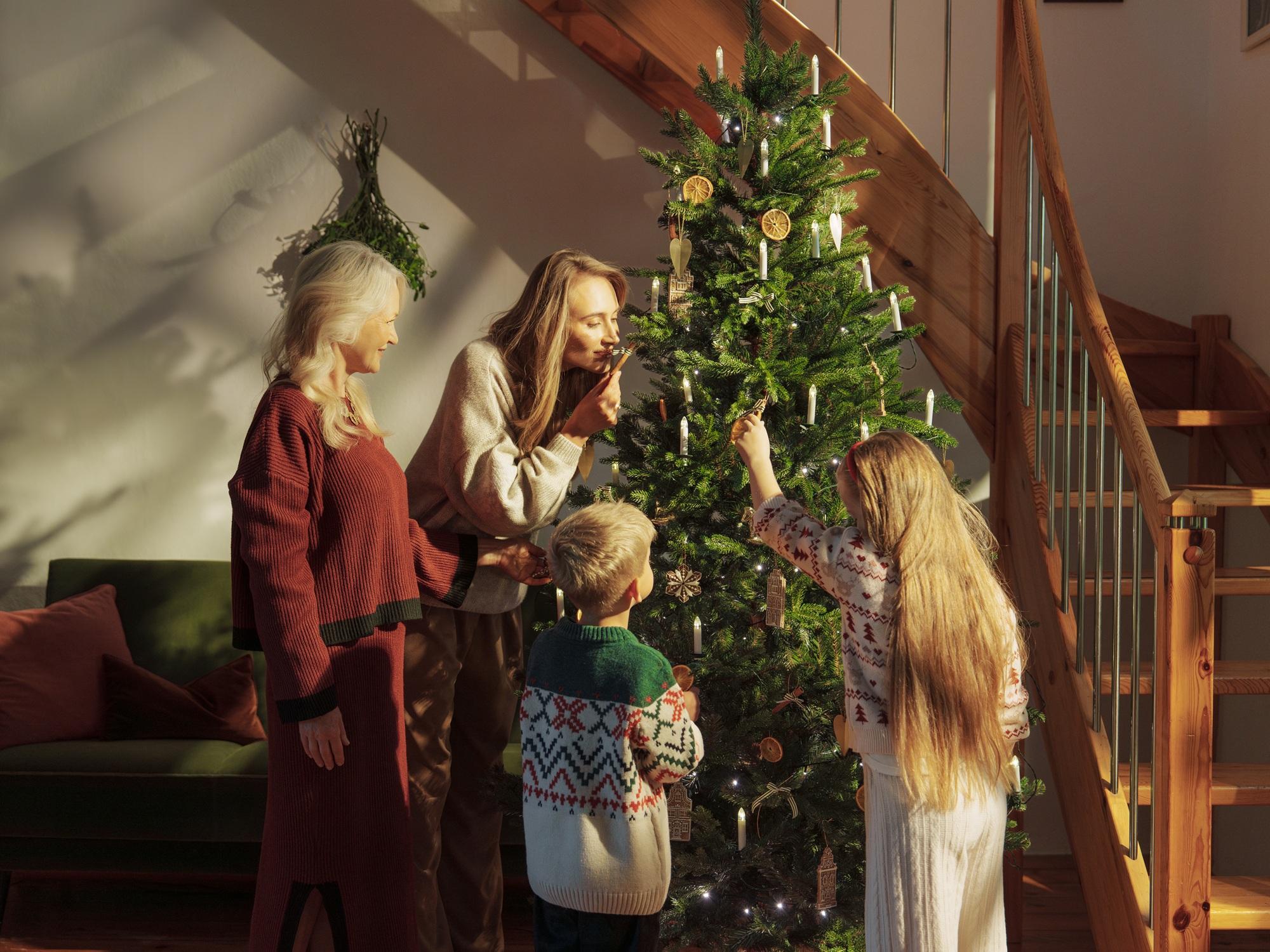Famille décorant ensemble le sapin de Noël FairyTrees FT33 pour les fêtes