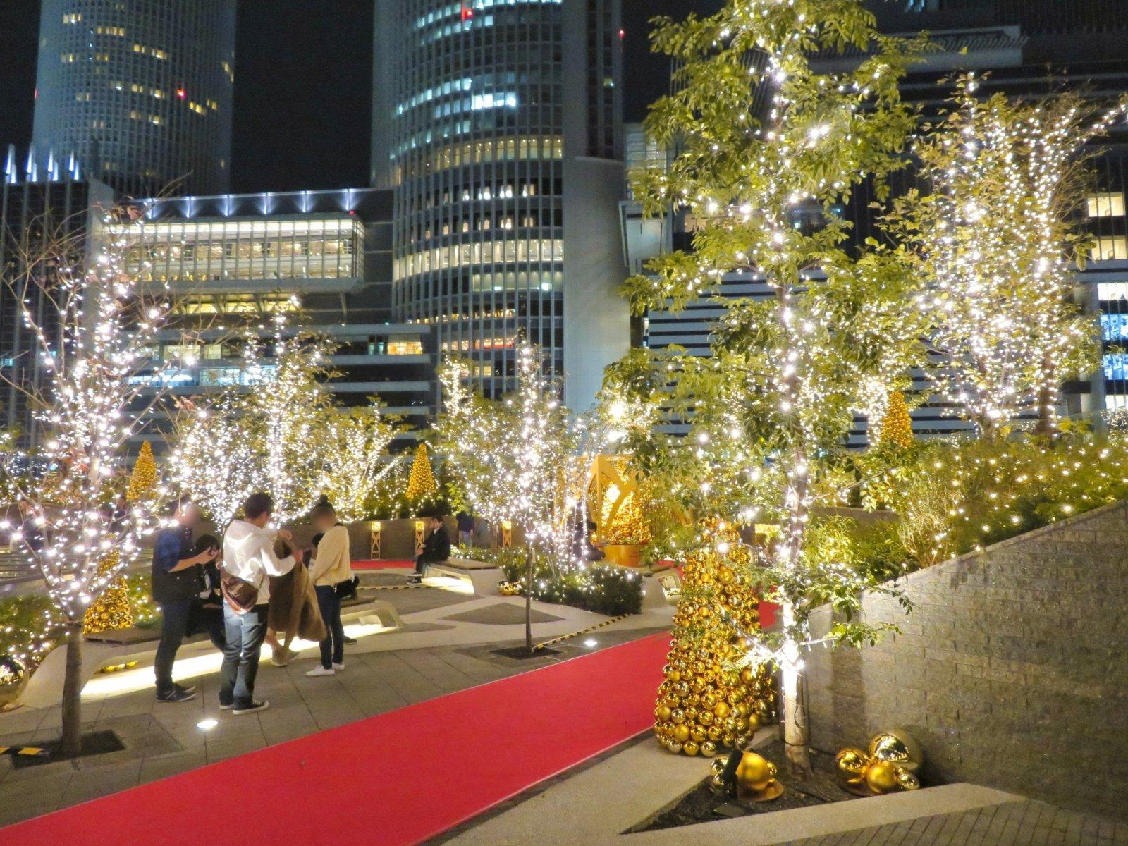 Une terrasse sur le toit du b&acirc;timent Dai-Nagoya &agrave; Tokyo est d&eacute;cor&eacute;e avec des illuminations festives et des sapins, entour&eacute;e de b&acirc;timents modernes.
