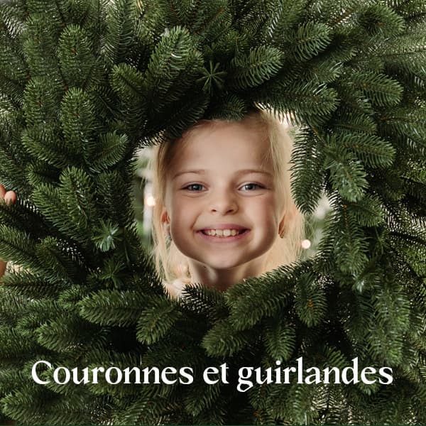 Une fillette regarde &agrave; travers une couronne de No&euml;l FairyTrees