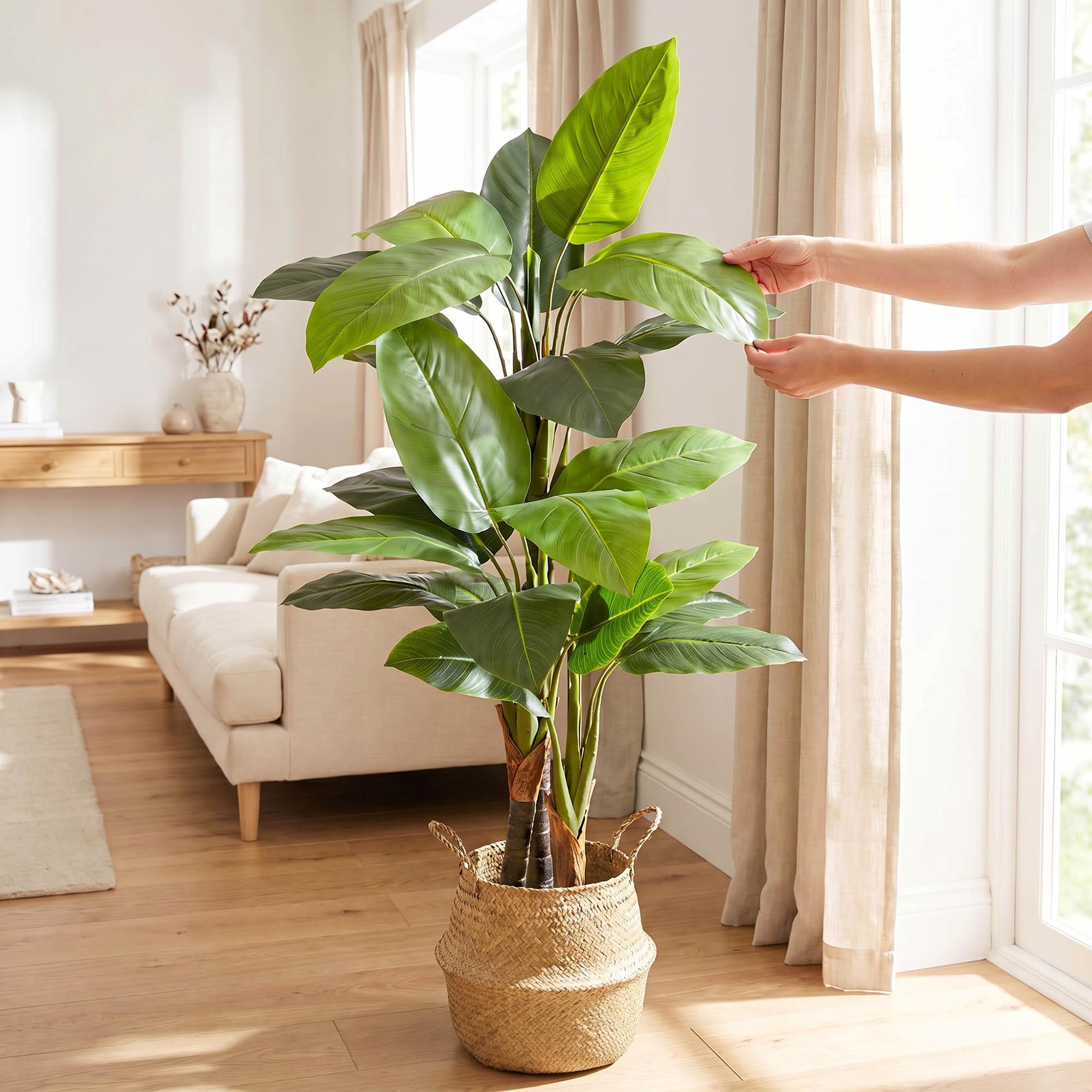 Des mains ajustent les feuilles du monstera artificiel sur tige de 160 cm FairyTrees, soulignant leur aspect naturel et leur souplesse.