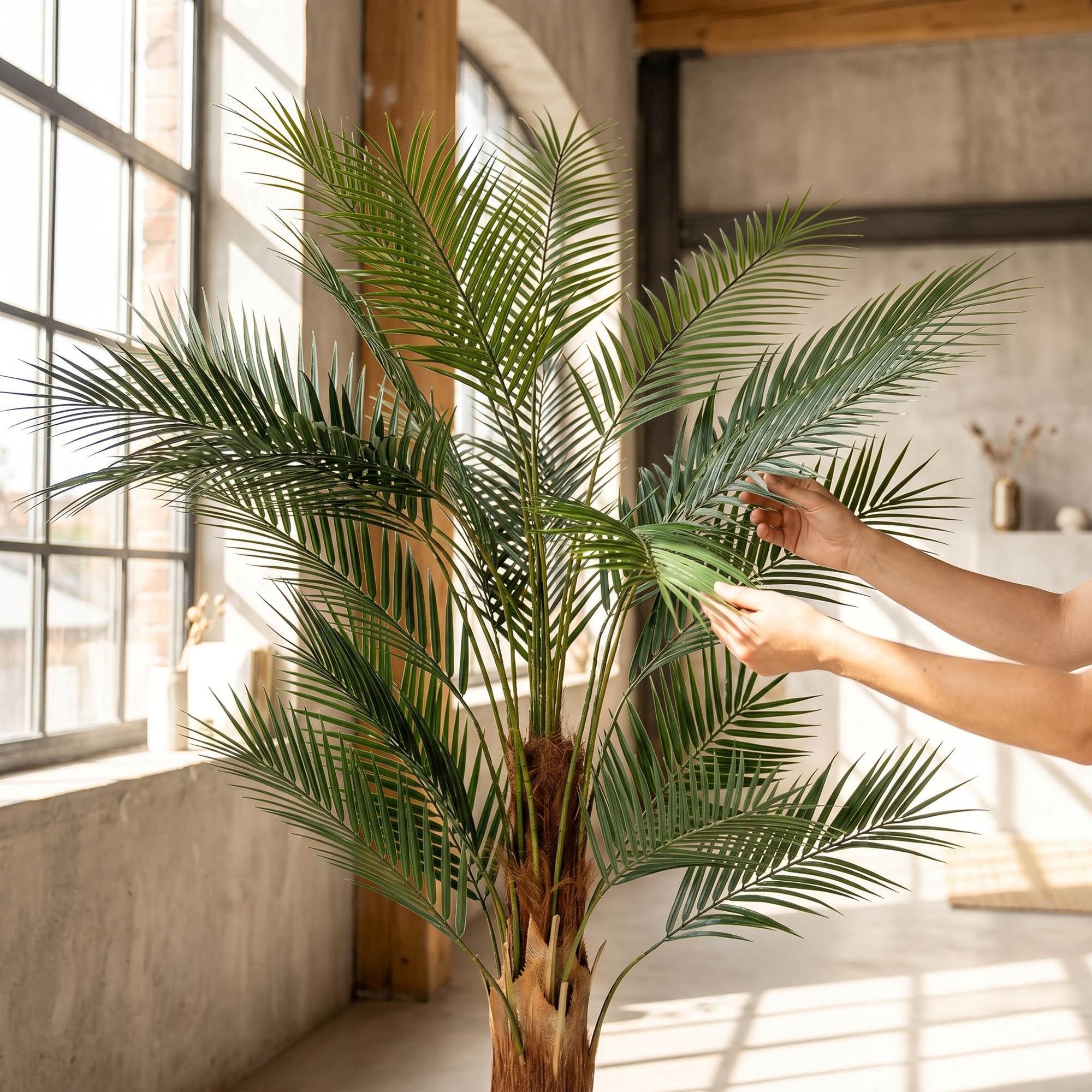 Des mains ajustent les feuilles du monstera artificiel sur tige de 160 cm FairyTrees, soulignant leur aspect naturel et leur souplesse.